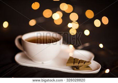 Cup Of Green Tea With Matcha Chocolate And Floers On Tray Over Lights. Good Morning. Breakfast.