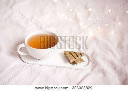 Cup Of Green Tea With Matcha Chocolate And Floers On Tray Over Lights. Good Morning. Breakfast.