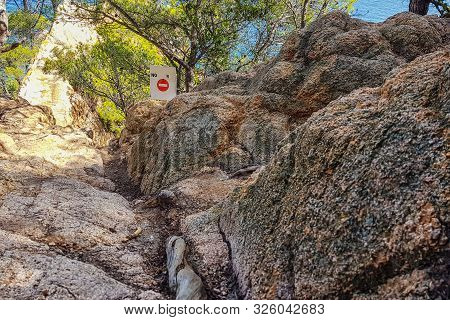 Dangerous Passage On A Rocky Seashore. The Sign Prohibiting Passage Is Set.