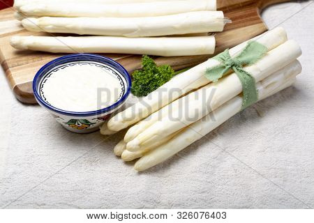 Bunch Of Fresh Uncooked White Asparagus And Hollandaise Sauce In Bowl