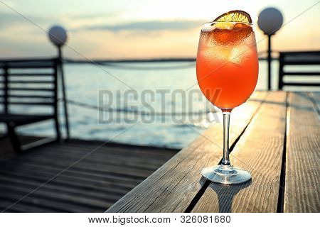 Glass Of Fresh Summer Cocktail On Wooden Table Outdoors At Sunset. Space For Text