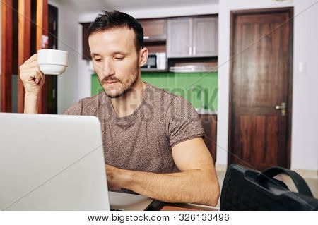 Bearden Pensive Man Drinking Cup Of Coffee And Looking At Programming Code On Laptop Screen