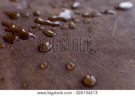 Transparent Water Drops Are Clearly Visible On A Mate Wooden Table.