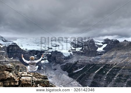 Woman Meditating On Rock In Front Of Pear With Glaciers And Snow. Meditation In Mountains.  Fairview