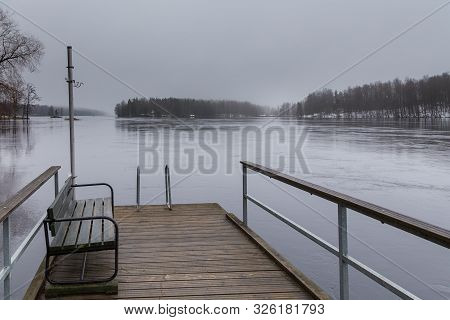 Small Pier At Beach On Lake Ruotsalainen, Bench On A Pier. Winter Landscape, Heinola, Finland.