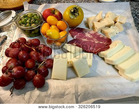 Red Wine And Assorted Cheese Plate, Smoked Beef, Ham, Salami, Green Olives, Fresh Ripe Persimmon Wit