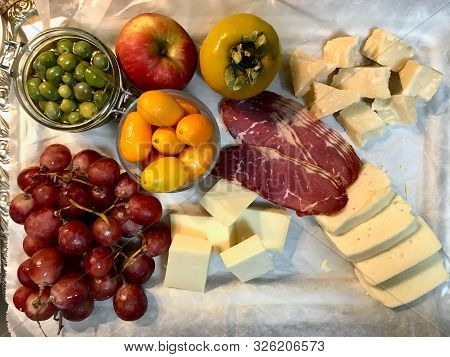 Red Wine And Assorted Cheese Plate, Smoked Beef, Ham, Salami, Green Olives, Fresh Ripe Persimmon Wit