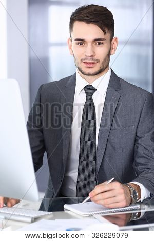 Businessman Working With Computer In Modern Office. Headshot Of Arab Male Entrepreneur Or Manager At