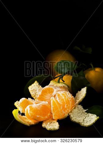 Peeled Fresh Clementine Or Tangerines With Leaves Located In A Corner On A Dark Slate Background. On
