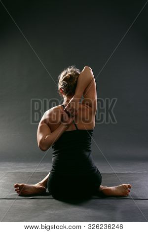 Young Girl In Black Sportswear Is Training In The Studio. Practice Yoga. Asana Pose Gomukhasana. Zen