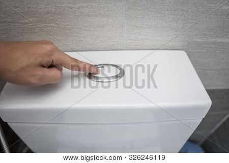 Close Up Of Finger Pushing A Flush Toilet Button For Cleaning A Toilet.