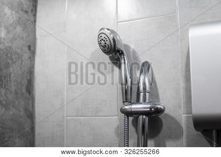 Instant Tankless Electric Water Heater Installed On Grey Tile Wall With Input And Output Pipe Outlet