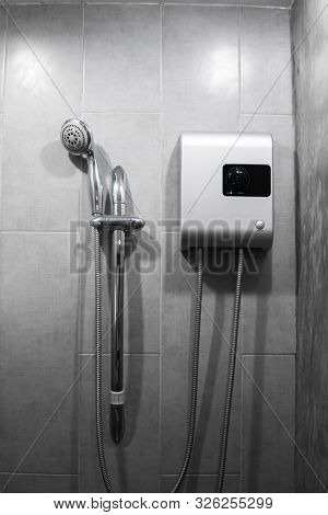 Instant Tankless Electric Water Heater Installed On Grey Tile Wall With Input And Output Pipe Outlet