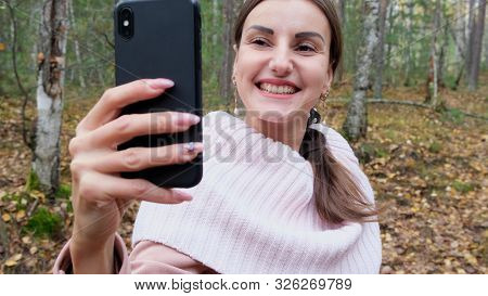 A Young Woman Takes Selfie On The Phone With Pleasure In The Spring Forest And Smiles. Slow Mo. Clos