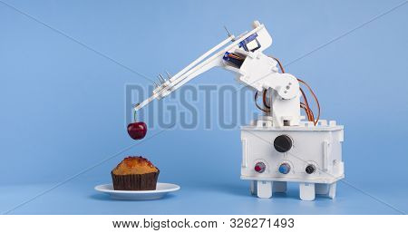 Innovative Kitchen Technology. Robot Cooking Dessert, Decorating Sweet Cupcake With Fresh Cherry, Bl