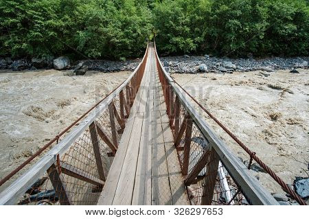 Hanged Rope Bridge Over The Fast Muddy River