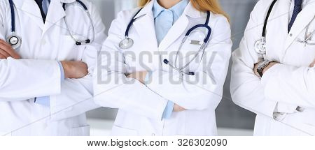 Group Of Modern Doctors Standing As A Team With Arms Crossed In Hospital Office, Close-up. Physician