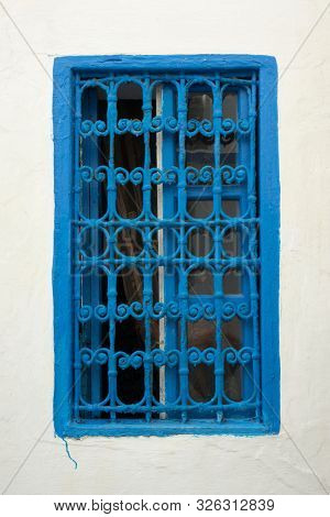 Traditional Moroccan window protected with a blue metal railing in Asilah, Morocco