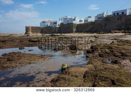 Low tide in the Atlantic Ocen in front of the historical rampart to protect Assilah, Morocco