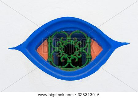 Moroccan colorful design window in the shape of an eye with a metal railing in Asilah, Morocco