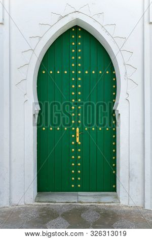 Green painted wooden door with gold colored decoration in the medina of Asilah, Morocco