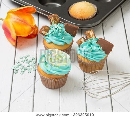 Cupcakes With Blue Cream, Chocolate And Candy In The Form Of Stars.