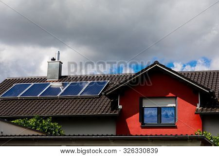 Solar Panels On The Roof Of A House In Cloudy Weather. Storm Clouds Block The Sunlight. The Concept 