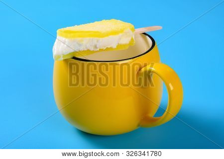 Yellow Popsicle With The Last Bit On A Cup On Blue Background