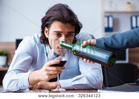 Male employee drinking alcohol and smoking cigarettes at workpla