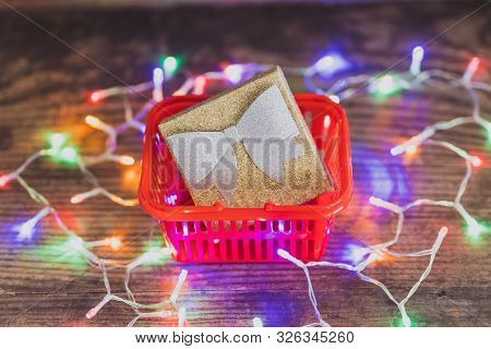 Christmas Present Box With Bow And Glitters Inside Shopping Basket Surrounded By Colorful Festive Fa