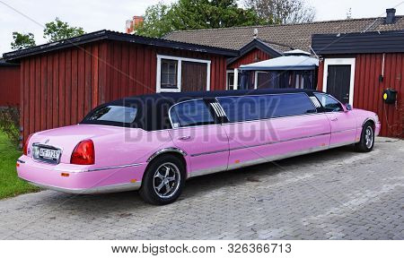 Umea, Sweden - September 15, 2019: A Pink Limo Stands On The Driveway With A Red House In The Backgr