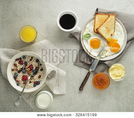 Breakfast Served With Oatmeal And Fruits, Fried Eggs With Bread And Jam With Butter On Table Top Vie