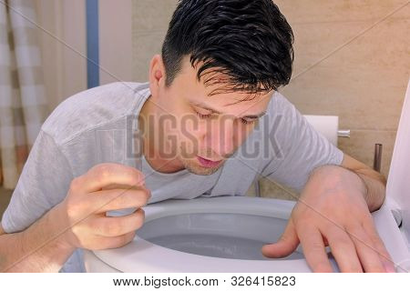 Portrait Of Man Is Vomiting In Toilet And Drinking Water Feeling Bad Having Flu. Food Poisoning And 