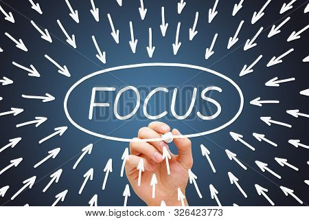 Hand Drawing Focus Arrows Concept With White Marker On Transparent Wipe Board Over Dark Blue Backgro