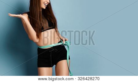 Closeup Of Happy Sporty Girl In Shorts And Sport Bralet With A Measure Tape Around Her Waist Holding