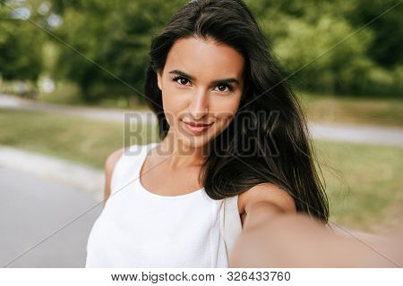 Close-up Portrait Of A Beautiful Young Brunette Smiling Woman Taking Self Portrait On Nature Backgro