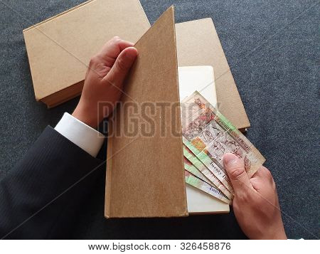 Hands Of A Businessman With Belizean Money And Books On The Table