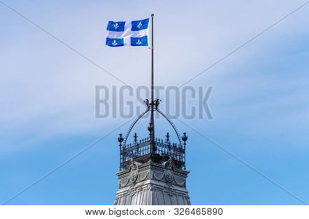 Quebec Flag Waving In The Wind Against Blue Sky In Quebec City.