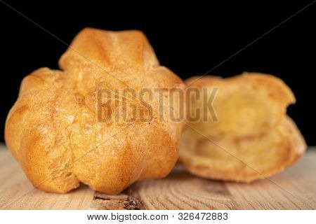 Group Of One Whole One Half Of Baked Golden Profiterole On Natural Wood Isolated On Black Glass