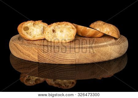 Group Of Four Halves Of Baked Golden Profiterole On Bamboo Plate Isolated On Black Glass