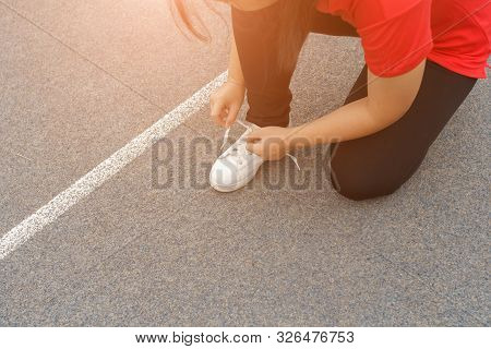 Close-up Of Sportgirl Tying Sneakers On Running Shoes Before Practice - Running Concept.