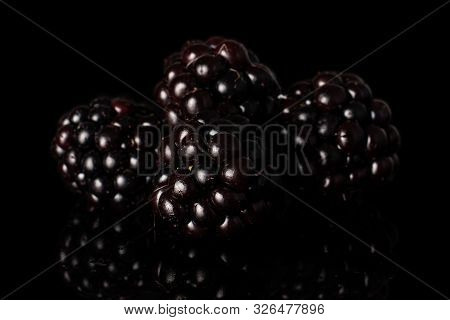 Group Of Four Whole Fresh Black Blackberry Isolated On Black Glass