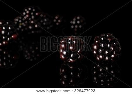 Lot Of Whole Fresh Black Blackberry Two In Focus Isolated On Black Glass