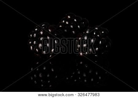 Group Of Three Whole Fresh Black Blackberry Isolated On Black Glass