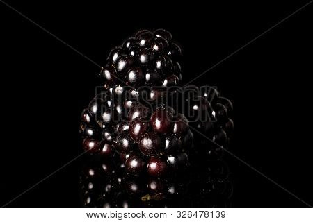 Group Of Four Whole Fresh Black Blackberry Isolated On Black Glass