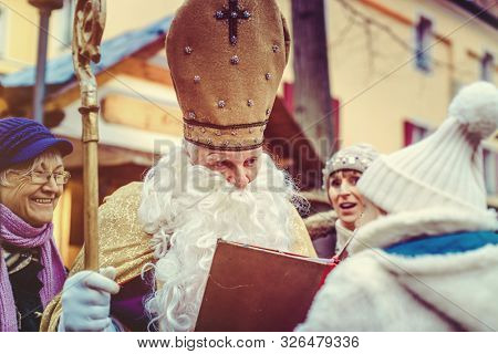 St Nicholas meeting a child on the Christmas Market while the family waits in the background