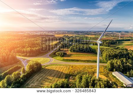 Wind Power Station. Aerial View. Several Wind Generators Standing At Top Of The Hill. Around Are Agr