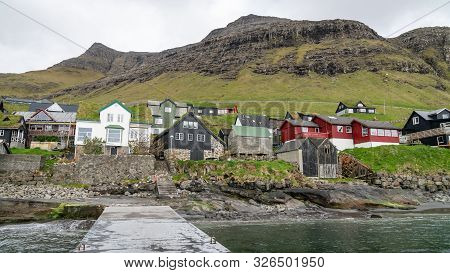 Bour, Faroe Islands - August 2019: Typical Nordic Village Overlooking A Fjord Surrounded By Green Mo