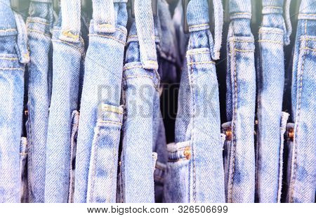 Blue Jeans Size Row In Warderobe Or On Store Hanger. Faded Jeans Retro Style Photo. Vintage Wear On 
