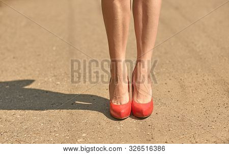 The Buzzing Legs Of A Girl In Red High-heeled Shoes. Numb Legs Of A Young Girl. Problems Caused By W